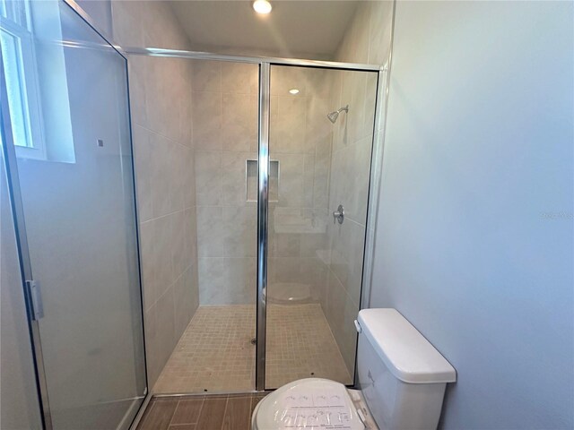 bathroom featuring toilet and a stall shower