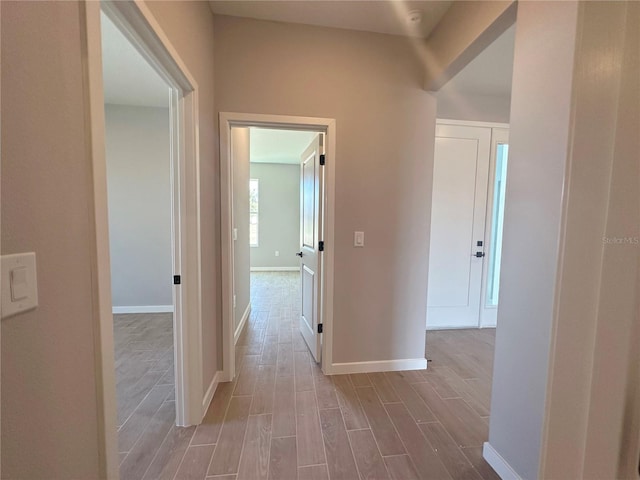 corridor featuring baseboards and wood finished floors