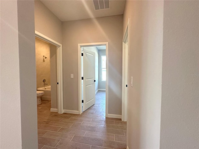 corridor with baseboards, visible vents, and wood tiled floor