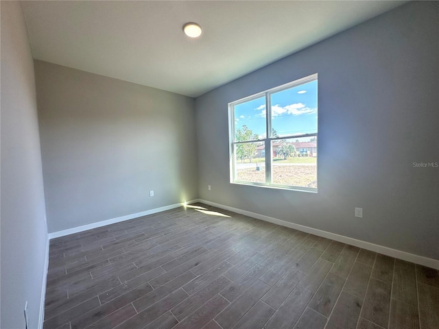 spare room with dark wood finished floors and baseboards