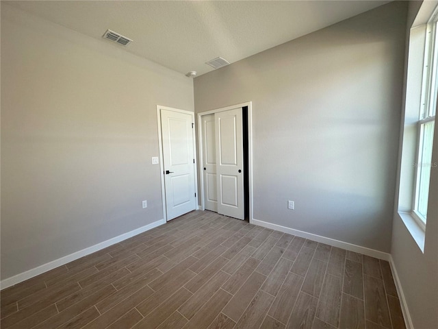 spare room featuring dark wood-style floors, visible vents, and baseboards