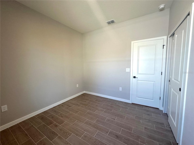 empty room with baseboards, visible vents, and wood finish floors