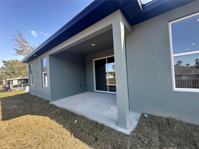 exterior space featuring a patio area, a yard, and stucco siding