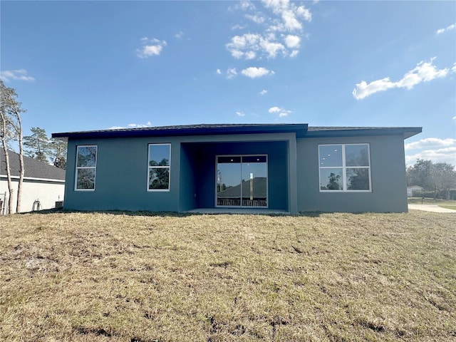 rear view of property with a yard and stucco siding