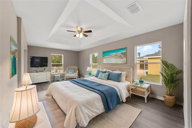 bedroom with a tray ceiling, ceiling fan, and wood-type flooring