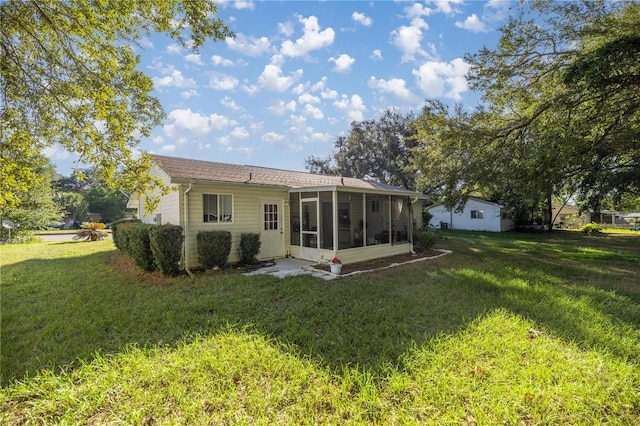 rear view of property with a lawn and a sunroom