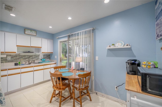 kitchen with white cabinets, light tile patterned floors, backsplash, and sink