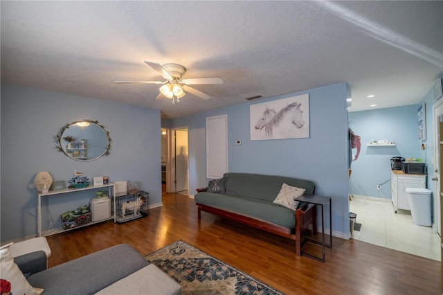 living room with wood-type flooring, a textured ceiling, and ceiling fan