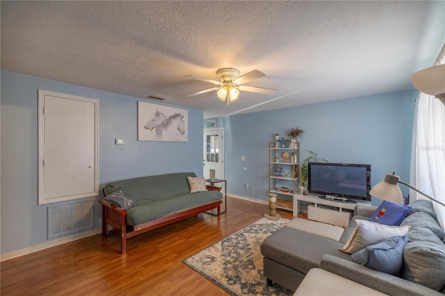 living room featuring ceiling fan, a textured ceiling, and hardwood / wood-style flooring