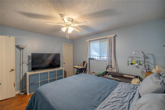 bedroom with hardwood / wood-style floors, ceiling fan, and a textured ceiling