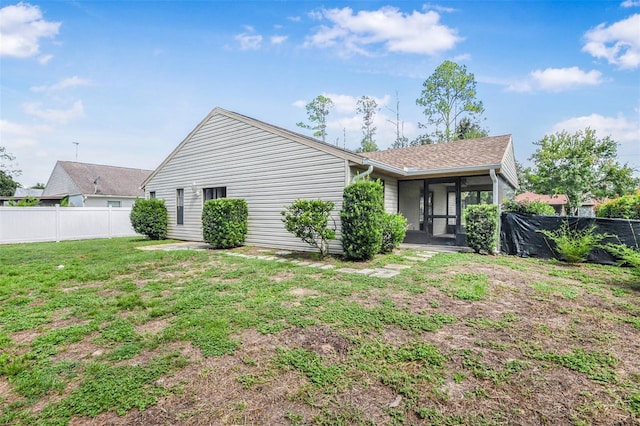 rear view of house with a yard and a sunroom