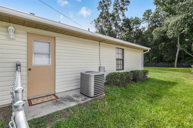 doorway to property with central AC unit and a lawn