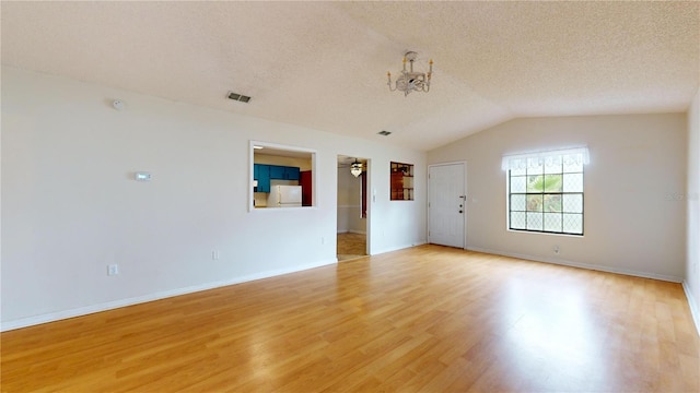 unfurnished room with a textured ceiling, light hardwood / wood-style flooring, ceiling fan with notable chandelier, and vaulted ceiling