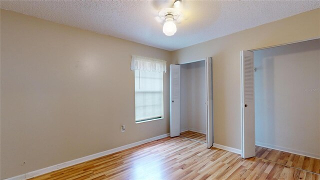 unfurnished bedroom featuring light wood-type flooring and a textured ceiling