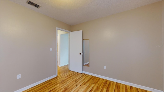 unfurnished room with light hardwood / wood-style floors and a textured ceiling