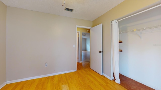 unfurnished bedroom featuring a textured ceiling, light wood-type flooring, and a closet