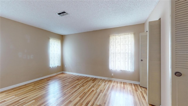 unfurnished bedroom with a closet, a textured ceiling, and light hardwood / wood-style flooring