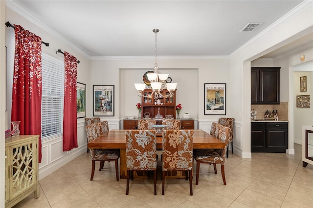 tiled dining space featuring a notable chandelier and crown molding