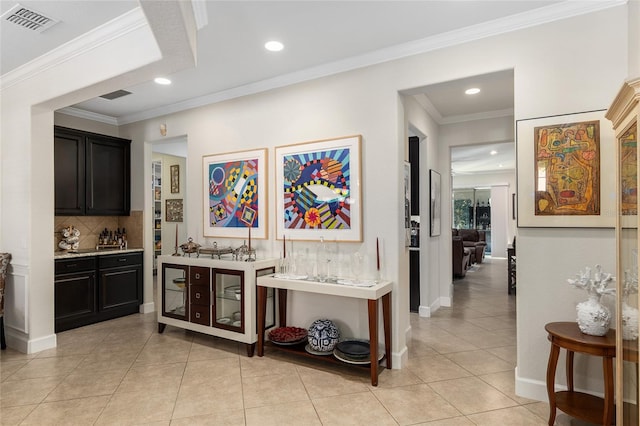 bar with decorative backsplash, ornamental molding, and light tile patterned floors