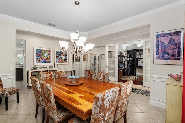 tiled dining area featuring crown molding and a chandelier