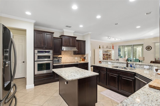 kitchen featuring sink, light tile patterned floors, ornamental molding, appliances with stainless steel finishes, and light stone counters