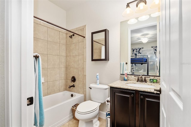 full bathroom with ceiling fan, tile patterned flooring, toilet, vanity, and tiled shower / bath