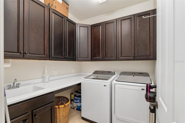 clothes washing area featuring cabinets, a textured ceiling, washer and clothes dryer, sink, and light tile patterned floors