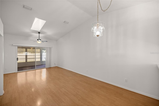 unfurnished living room featuring ceiling fan with notable chandelier, hardwood / wood-style flooring, and lofted ceiling with skylight