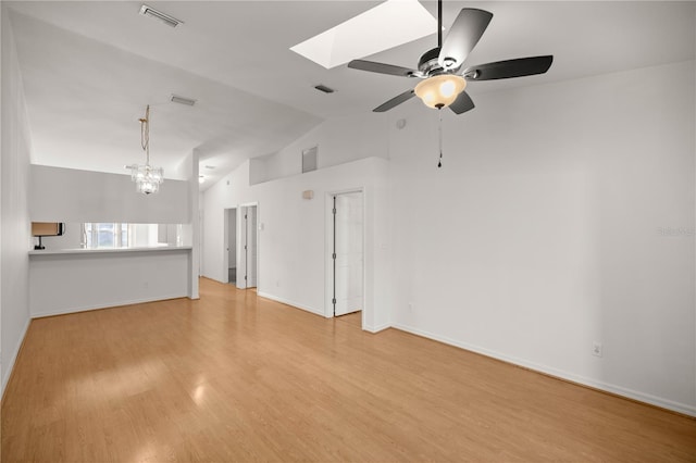 unfurnished living room featuring ceiling fan with notable chandelier, light hardwood / wood-style flooring, and vaulted ceiling with skylight