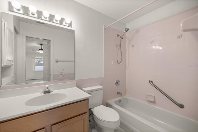 full bathroom with ceiling fan, a textured ceiling, toilet, vanity, and tiled shower / bath