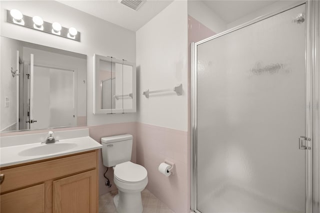 bathroom featuring vanity, toilet, walk in shower, and tile walls