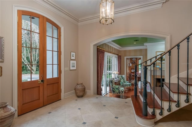 foyer featuring a wealth of natural light, french doors, crown molding, and a notable chandelier