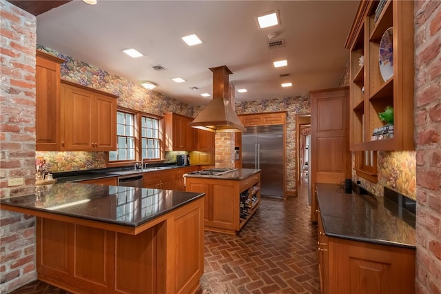 kitchen featuring kitchen peninsula, appliances with stainless steel finishes, island range hood, dark stone countertops, and a center island