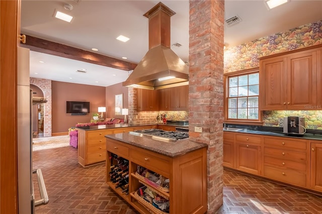 kitchen with stainless steel gas stovetop, decorative backsplash, island exhaust hood, and kitchen peninsula