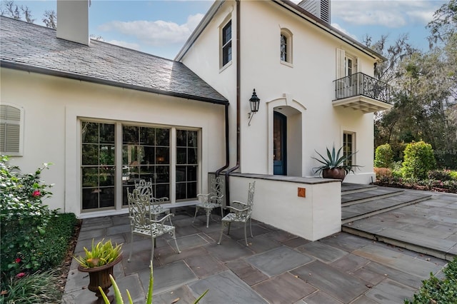 back of property featuring a balcony and a patio area