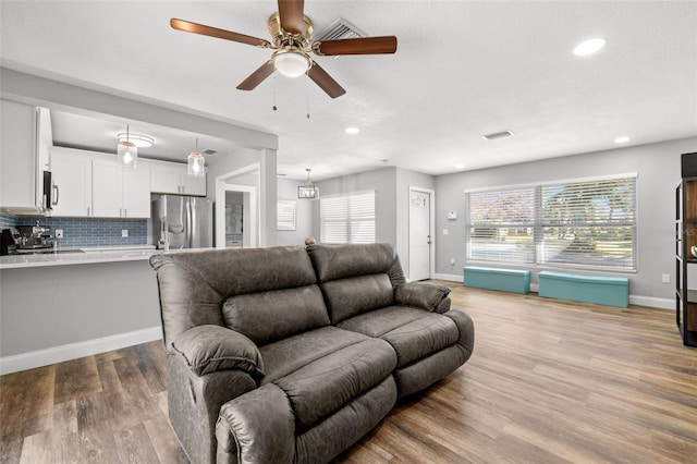 living room with ceiling fan and light wood-type flooring