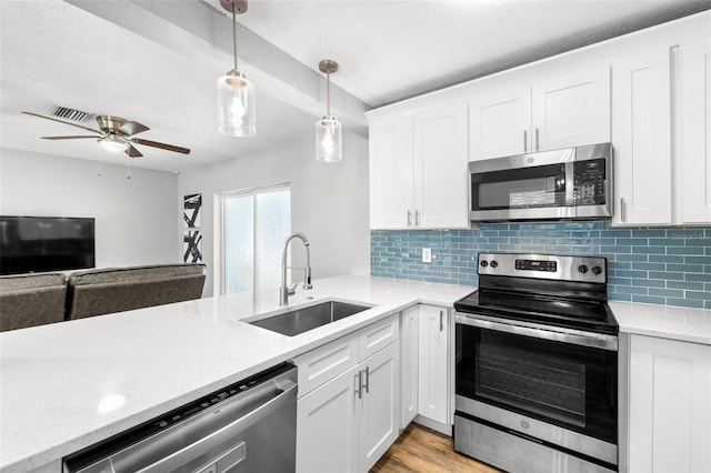 kitchen with appliances with stainless steel finishes, sink, decorative light fixtures, white cabinets, and light hardwood / wood-style floors