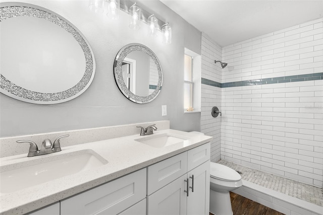 bathroom featuring tiled shower, vanity, wood-type flooring, and toilet