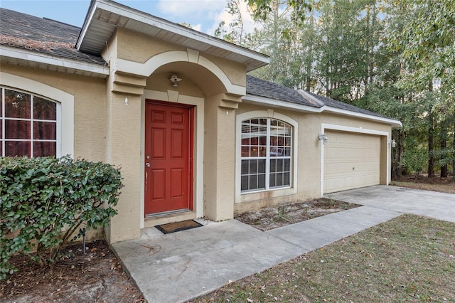 20390 SW 57th St, Dunnellon, FL 34431 - doorway to property featuring stucco siding, a garage, driveway, and roof with shingles