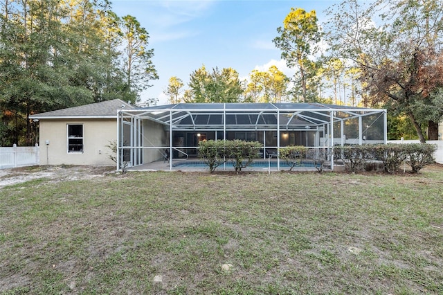 rear view of property featuring a fenced in pool, glass enclosure, and a lawn