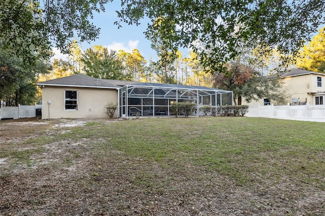 rear view of house with a lawn and a lanai