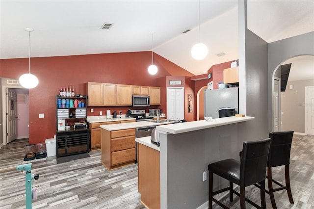 kitchen with hanging light fixtures, stainless steel appliances, high vaulted ceiling, a breakfast bar, and light wood-type flooring