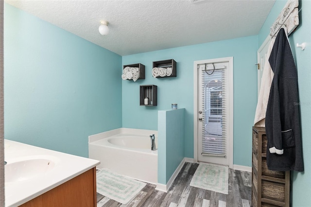 20390 SW 57th St, Dunnellon, FL 34431 - full bathroom featuring vanity, a garden tub, wood finished floors, a textured ceiling, and baseboards