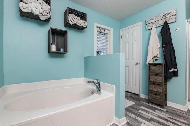 bathroom featuring hardwood / wood-style floors, a textured ceiling, and a tub to relax in