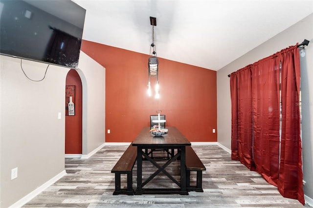 dining area with wood-type flooring and vaulted ceiling