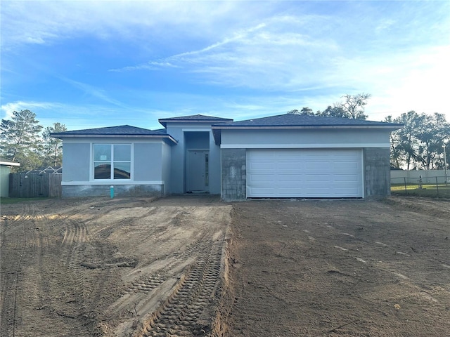 view of front of property featuring a garage, driveway, fence, and stucco siding