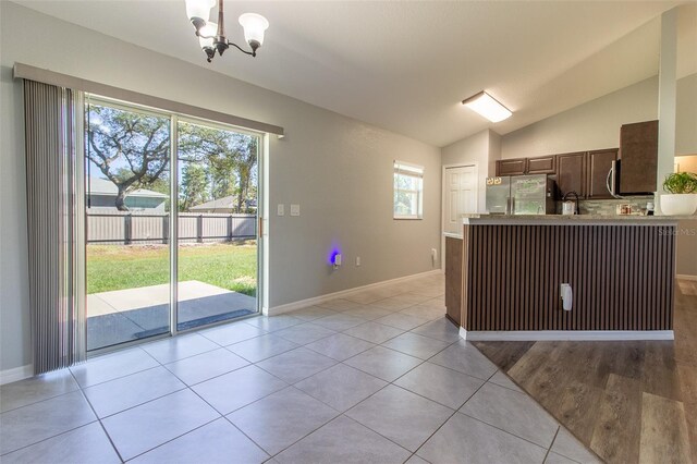 17023 SW 41st Avenue Rd, Ocala, FL 34473 - kitchen with dark brown cabinetry, an inviting chandelier, lofted ceiling, light tile patterned floors, and appliances with stainless steel finishes