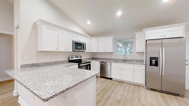 kitchen with kitchen peninsula, stainless steel appliances, sink, white cabinets, and lofted ceiling