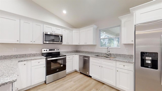 kitchen featuring white cabinets, light hardwood / wood-style floors, stainless steel appliances, and vaulted ceiling