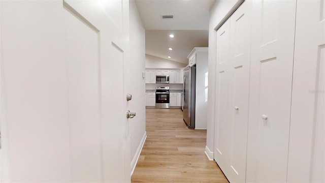 hall featuring light hardwood / wood-style floors and lofted ceiling